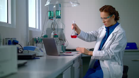 Woman-scientist-studying-chemical-liquid-in-lab-flask.-Chemical-engineering